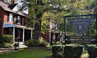 Historic house and sign at the Frederica Township Historic Village in green, tree-lined surroundings