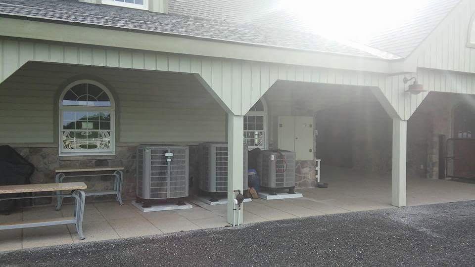Covered outdoor seating area with benches, air conditioners, and a parked scooter beside a building