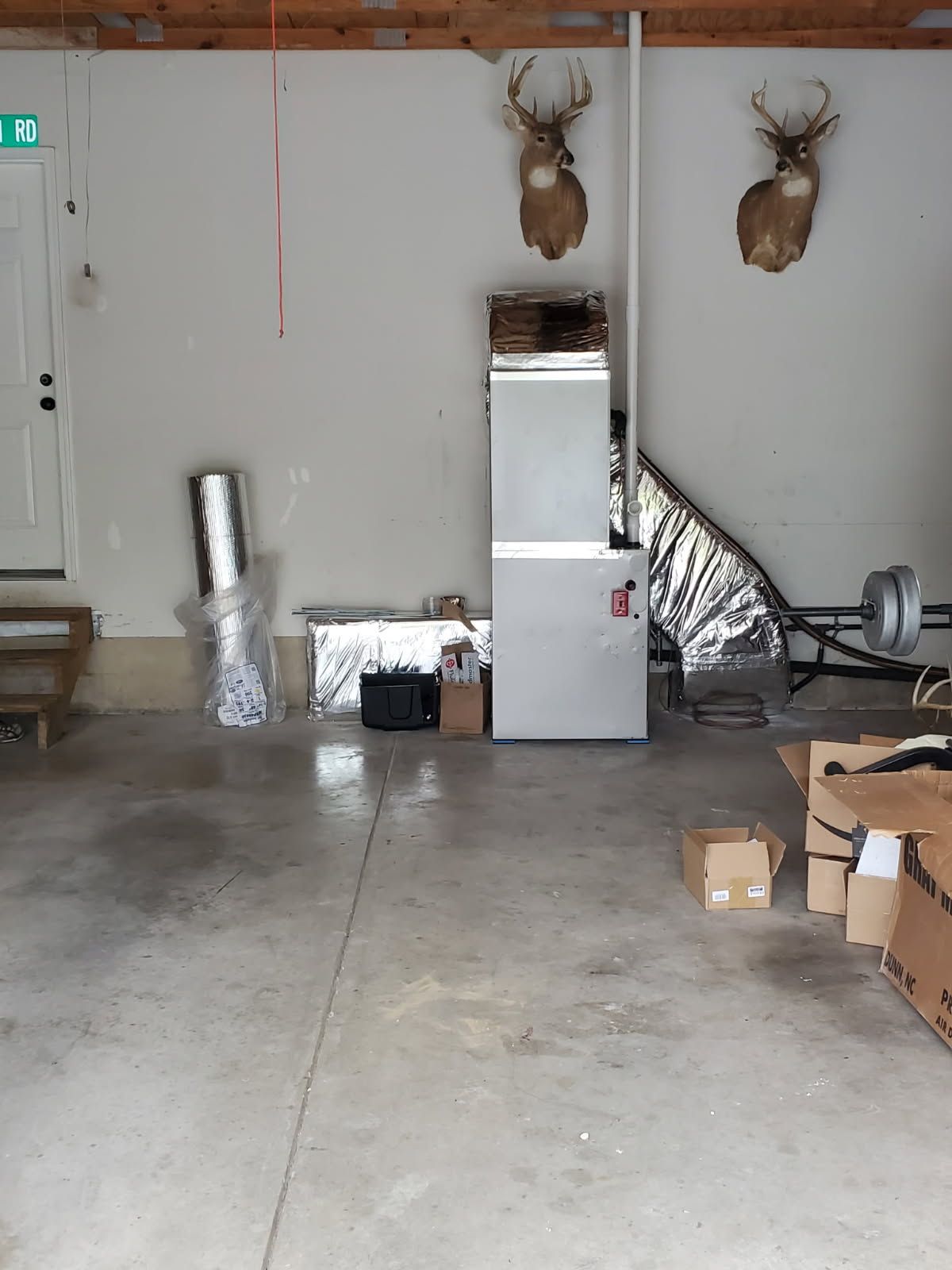 Garage with two mounted deer heads, stacked appliances, boxes, and a concrete floor