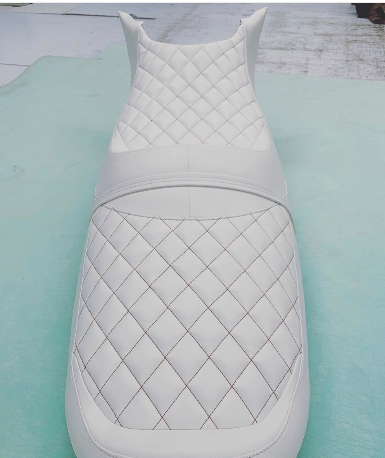 Jet ski seat with orange diamond stitching on white vinyl