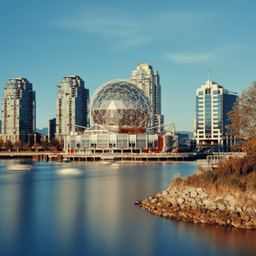 Science World building with its geodesic dome, waterfront and skyscrapers on a sunny day.