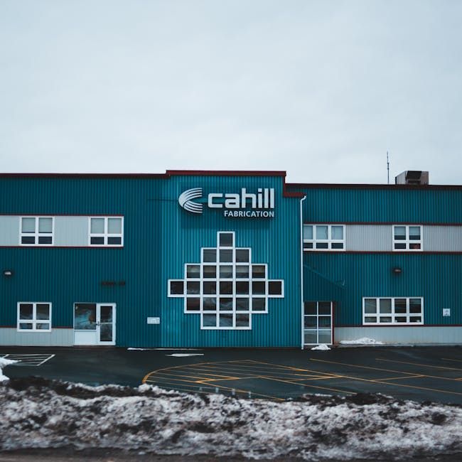 Blue Cahill Fabrication building with white windows and sign, snow in the foreground.