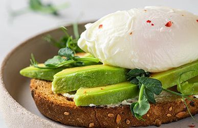 a close up of a sandwich with avocado and a poached egg on a plate .