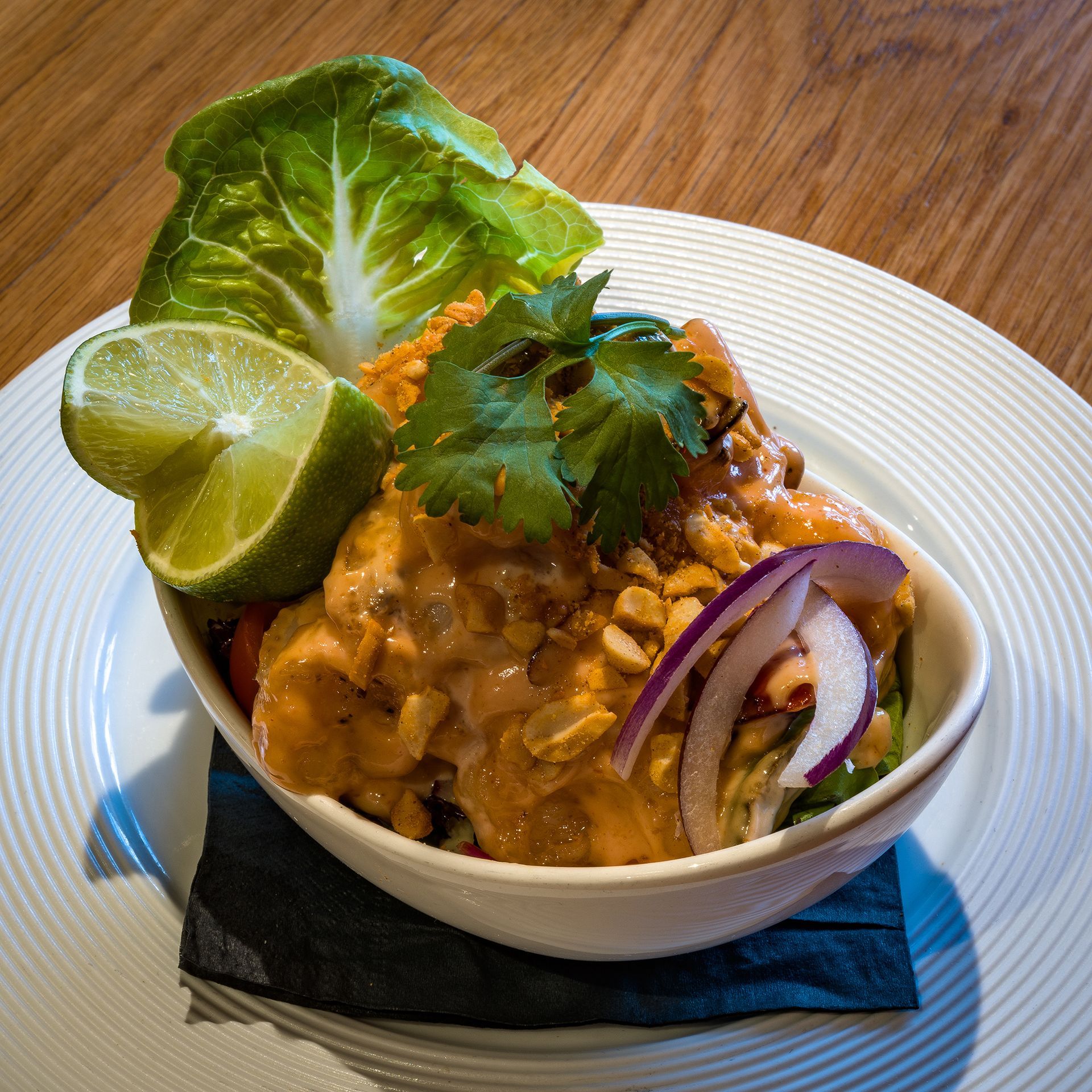 a bowl of food with lettuce and lime slices on a plate