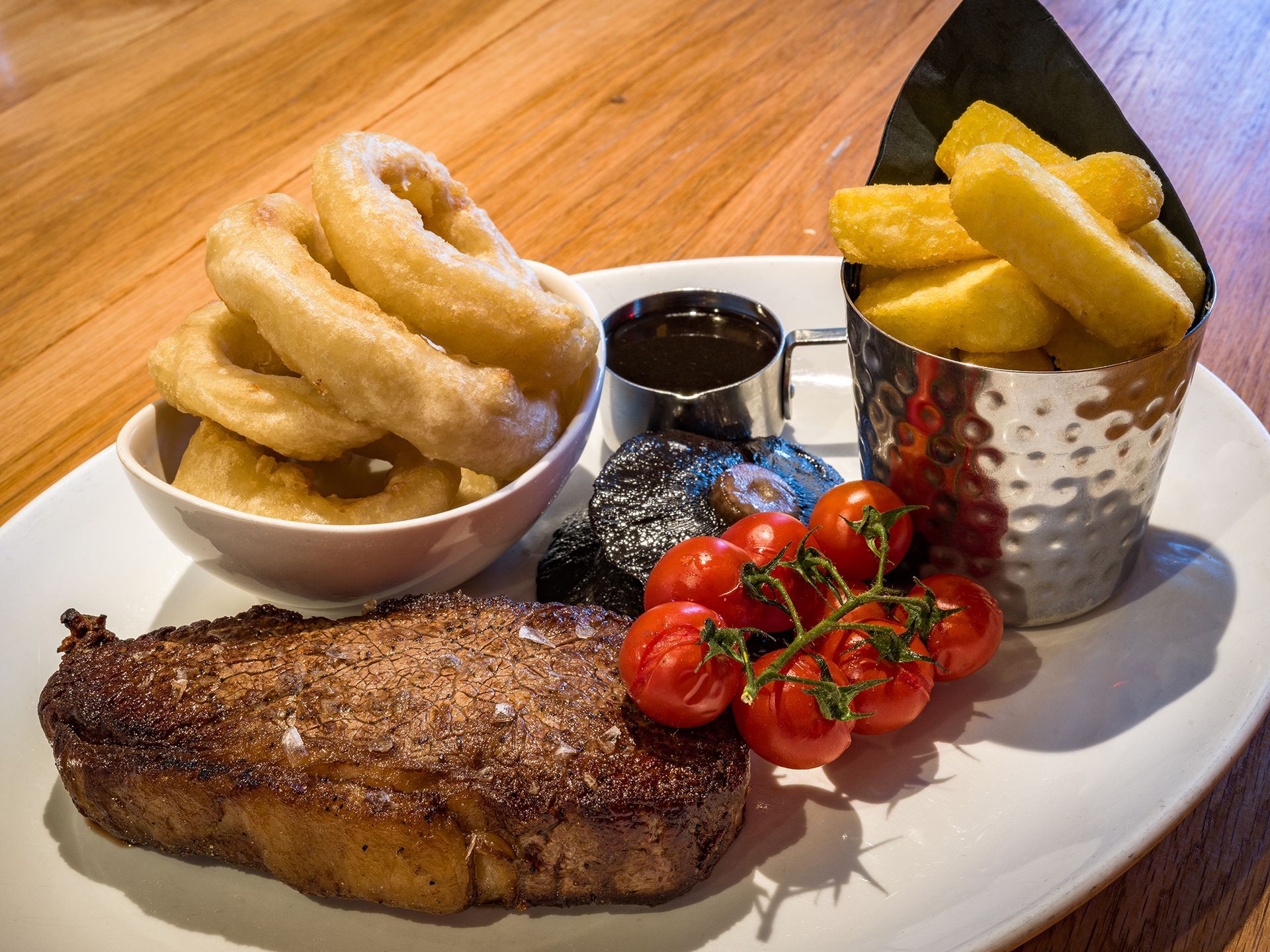 a white plate topped with a steak onion rings and french fries