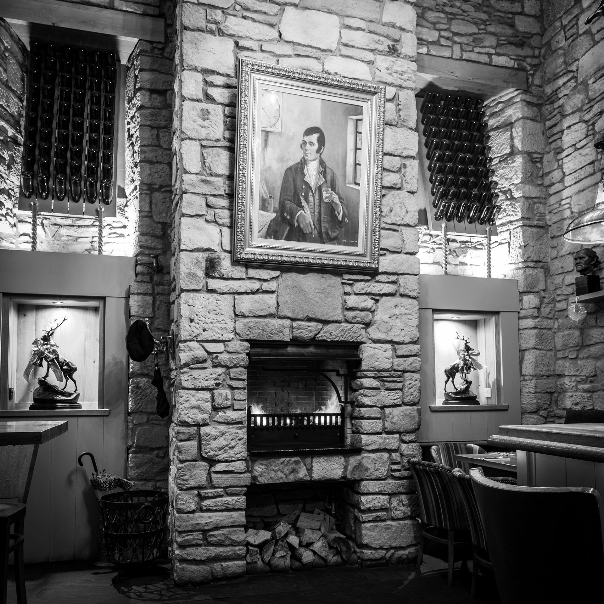 a black and white photo of a fireplace with a painting above it