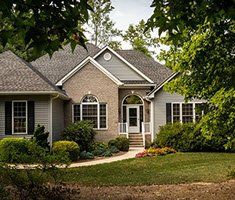 A large house with a lush green lawn and trees in front of it.