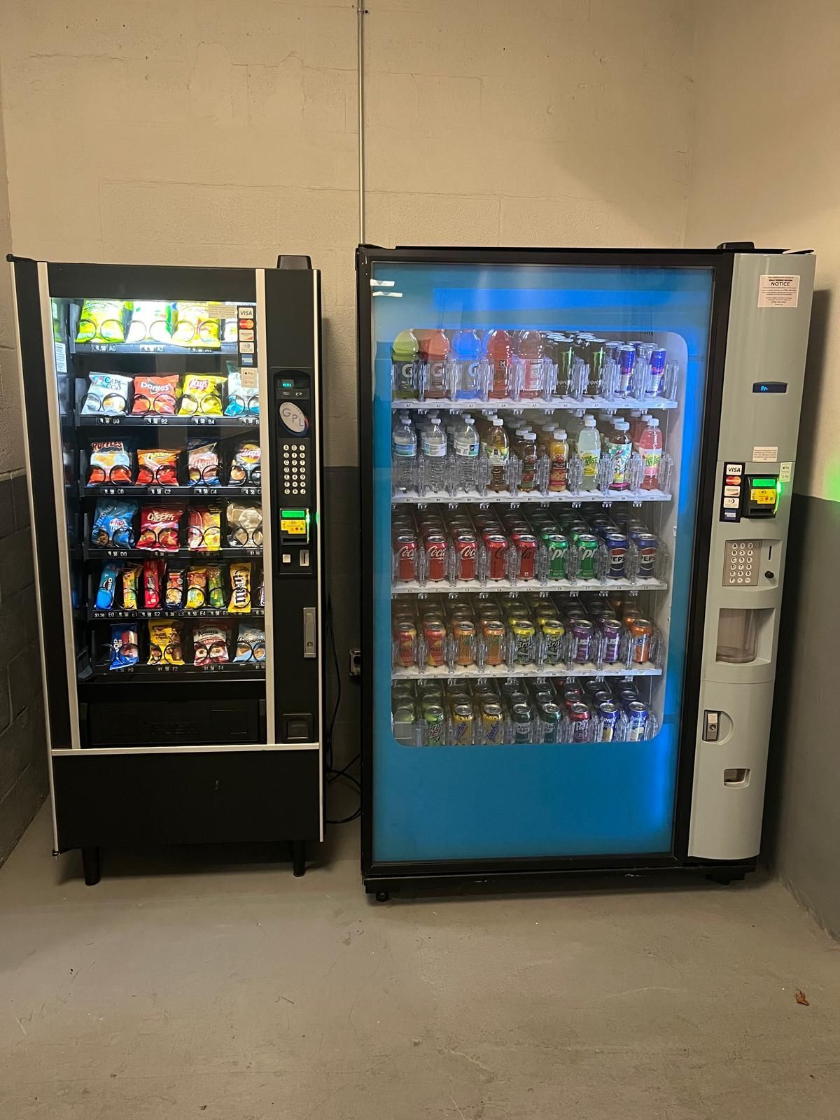 Two vending machines are sitting next to each other in a room.