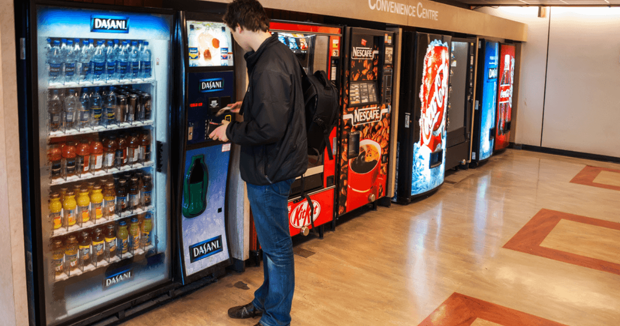A man is standing in front of a row of vending machines.