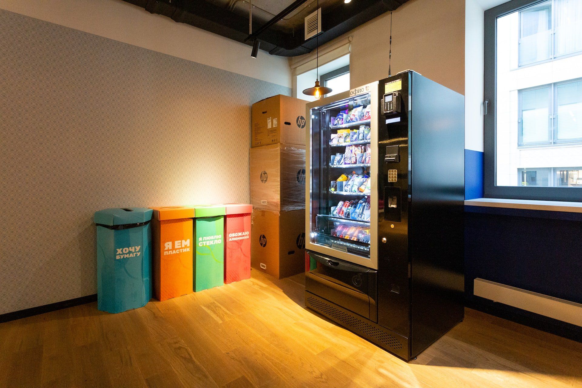 A room with a vending machine and trash cans on the floor.
