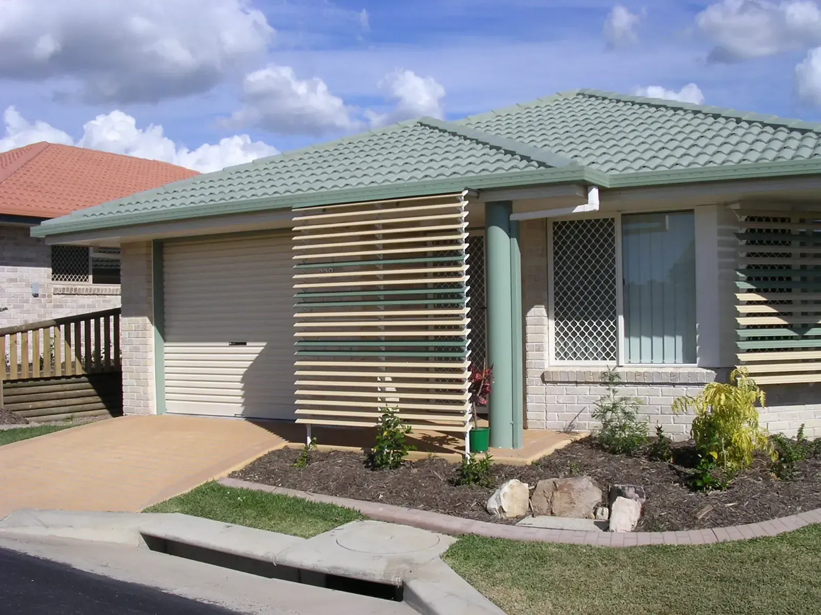 House With a Green Tiled Roof, a Closed Garage, and a Slatted Timber Privacy Screen — Advantage Screen And Blinds Rockhampton in Rockhampton, QLD
