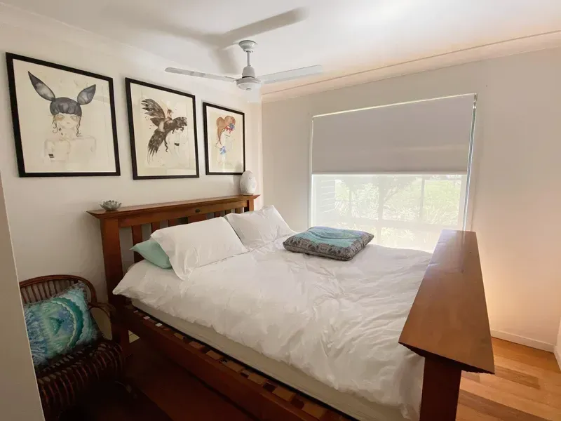 A Bedroom With a Wooden Bed Frame, White Bedding — Advantage Screen And Blinds Rockhampton in Rockhampton, QLD