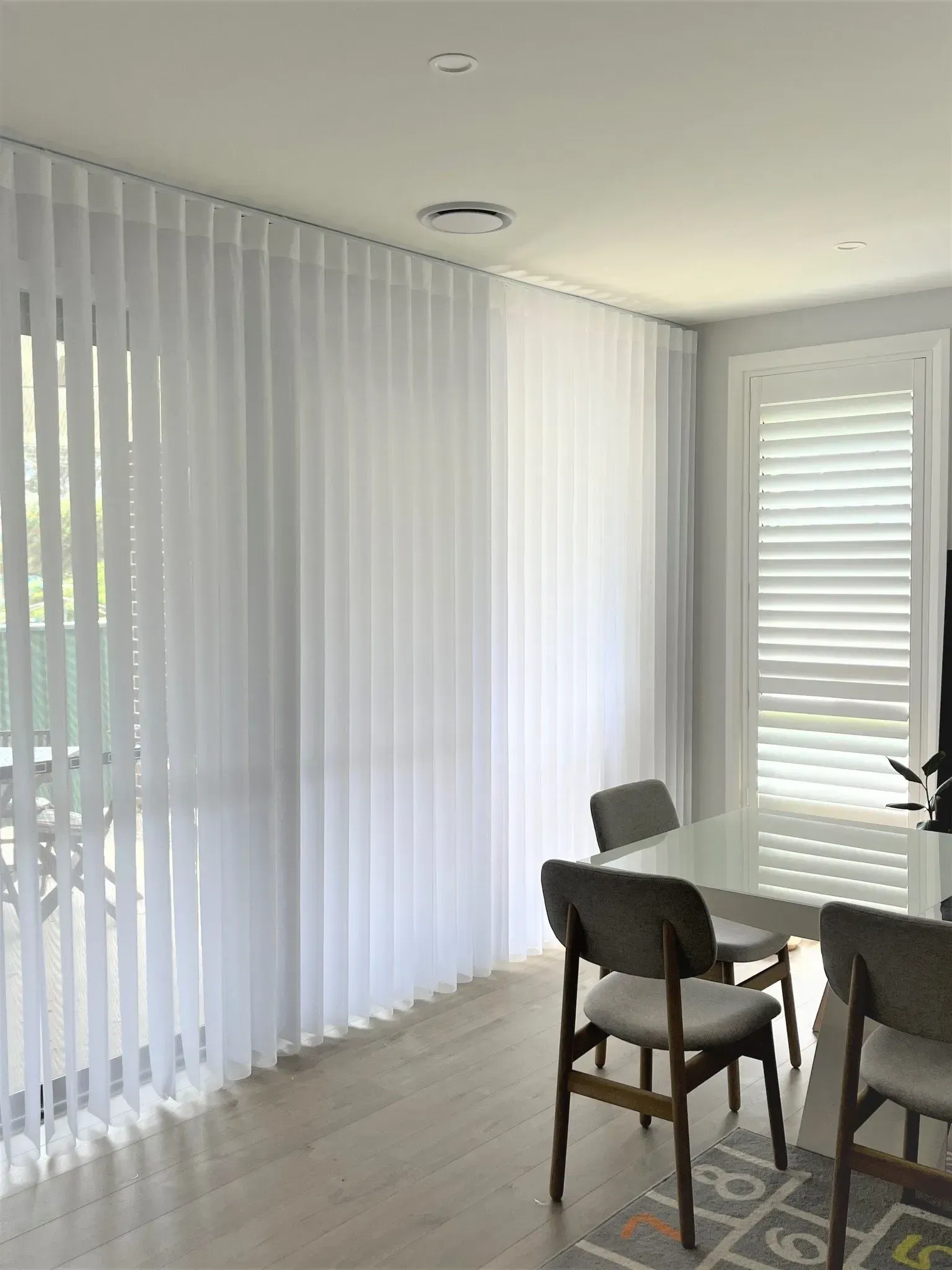 Bright Dining Area With Tall White Vertical Blinds and Shutters — Advantage Screen And Blinds Rockhampton in Rockhampton, QLD