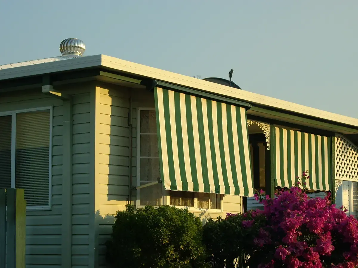 Home Exterior With a Green and White Striped Awning Over the Windows — Advantage Screen And Blinds Rockhampton in Rockhampton, QLD