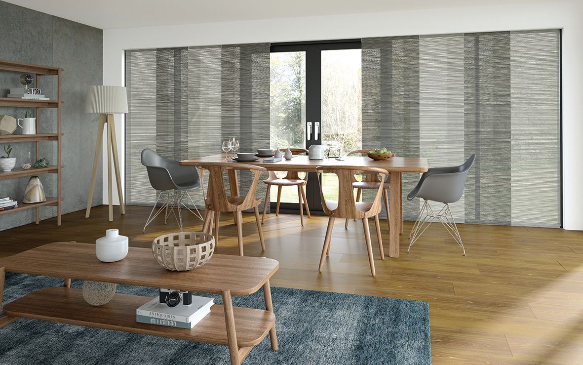 Modern dining room with wooden table, gray chairs, large windows, and a blue rug — Advantage Screen And Blinds Rockhampton in Rockhampton, QLD