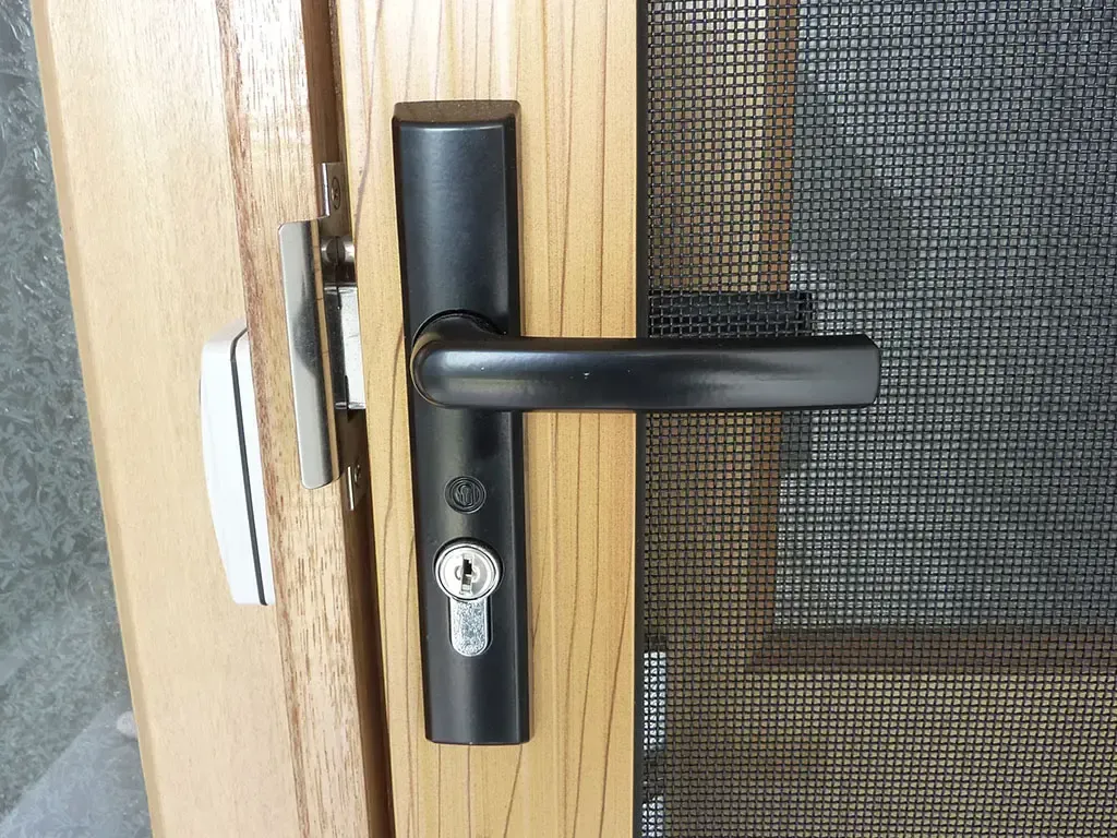 Door Handle With a Lock is Installed on a Wooden Door Next to a Mesh Screen — Advantage Screen And Blinds Rockhampton in Rockhampton, QLD