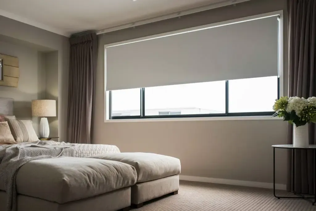 Bedroom With a Bed, Table Lamp, Floral Arrangement, and a Large Window With Shades — Advantage Screen And Blinds Rockhampton in Rockhampton, QLD