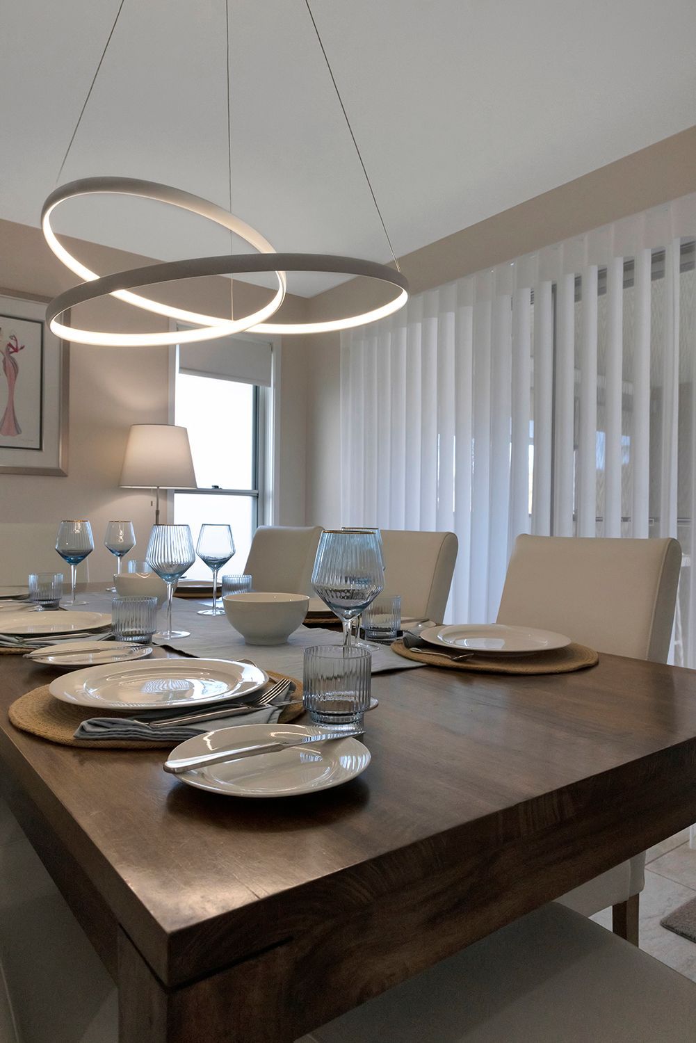 Modern dining room with a set table, white chairs, and circular pendant lights over a wooden table — Advantage Screen And Blinds Rockhampton in Rockhampton, QLD