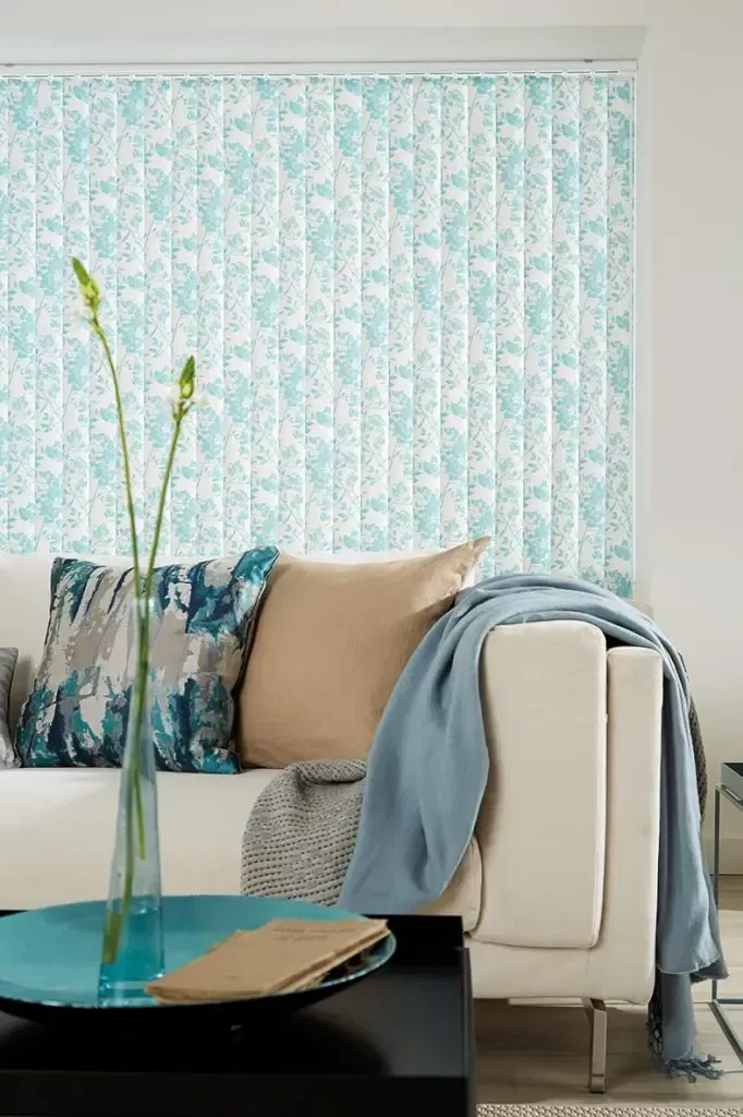 Living Room With a White Sofa Adorned With Beige and Blue Pillows and a Floral-patterned Vertical Blind — Advantage Screen And Blinds Rockhampton in Rockhampton, QLD