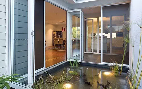 Modern Home With Floor-to-ceiling Glass Sliding Doors Opening Onto an Interior Courtyard — Advantage Screen And Blinds Rockhampton in Rockhampton, QLD