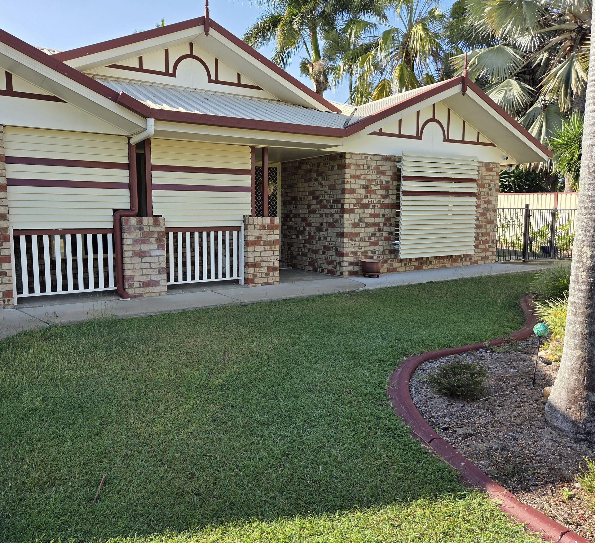 Single-story house with striped exterior, stone accents, front porch, and neatly landscaped lawn. — Advantage Screen And Blinds Rockhampton in Rockhampton, QLD