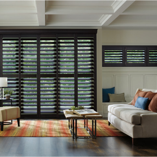 Modern living room with black shutters, beige sofa, colorful rug, and coffee table near a window wall — Advantage Screen And Blinds Rockhampton in Rockhampton, QLD