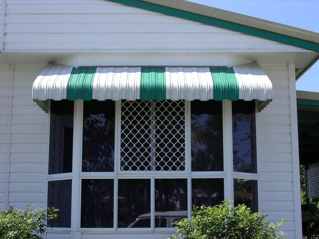 Green-and-white striped awning over a white house window with diamond lattice security bars — Advantage Screen And Blinds Rockhampton in Rockhampton, QLD