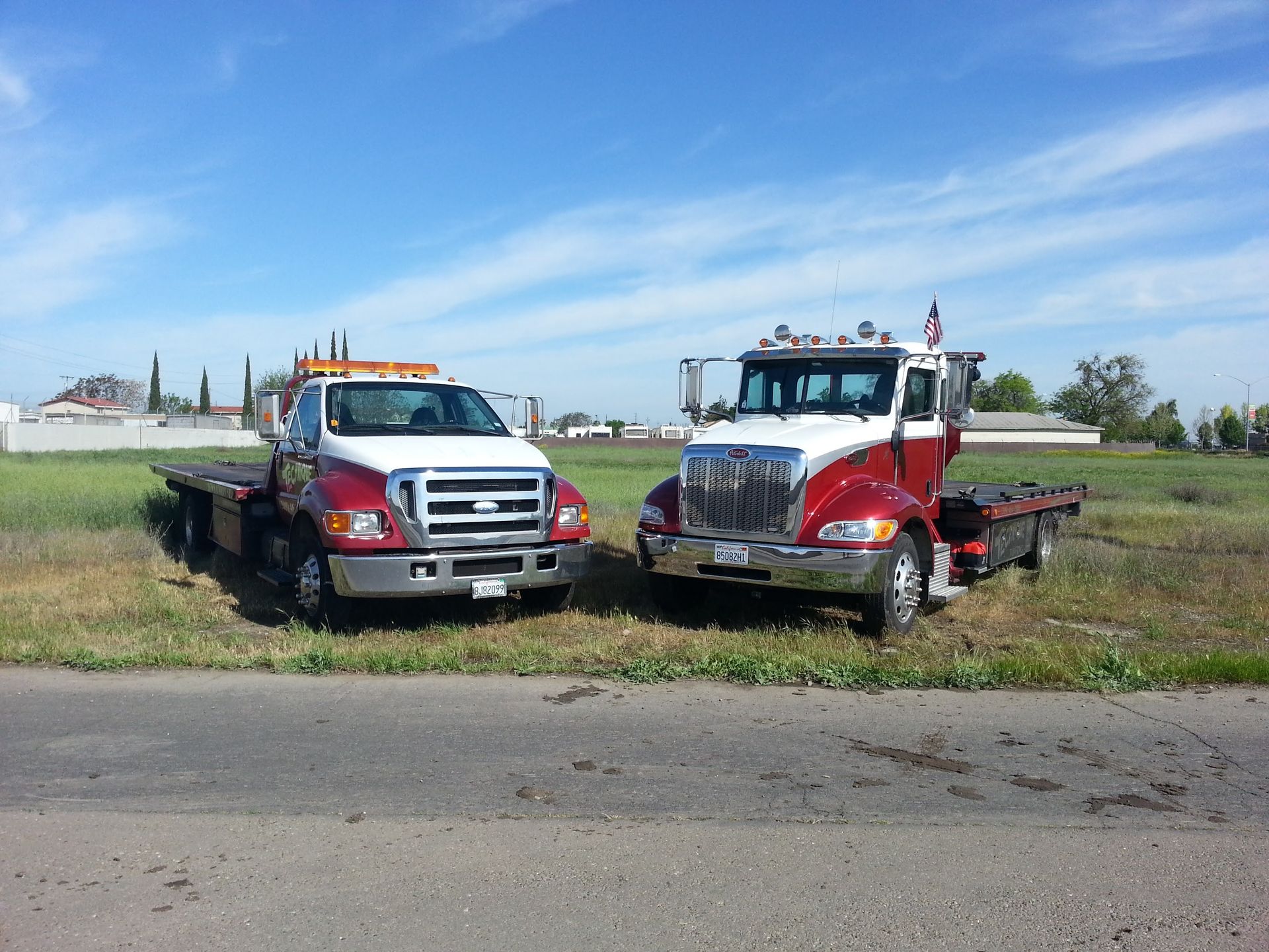 Two tow trucks are parked on the side of the road