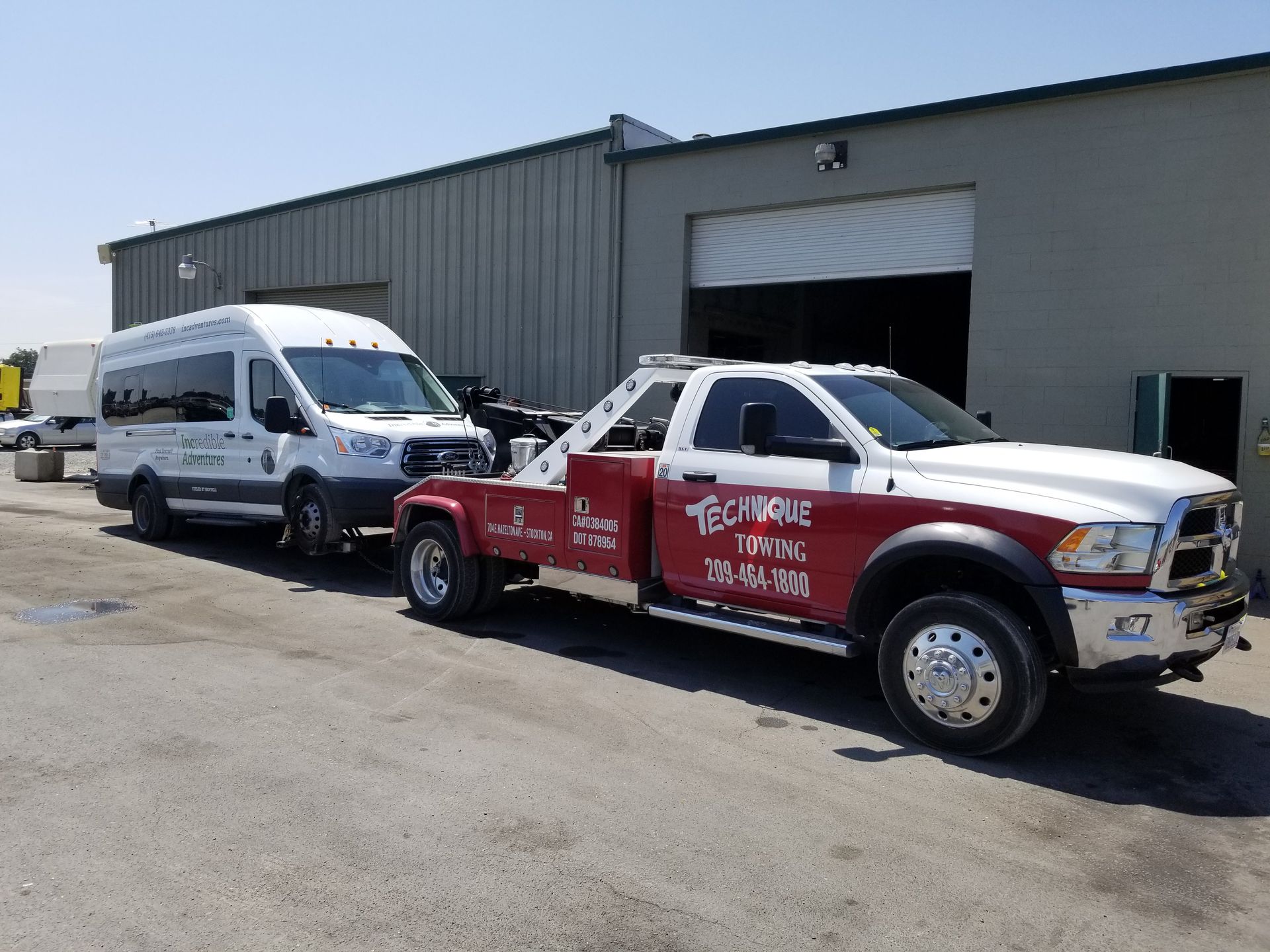 A white van is being towed by a red tow truck.