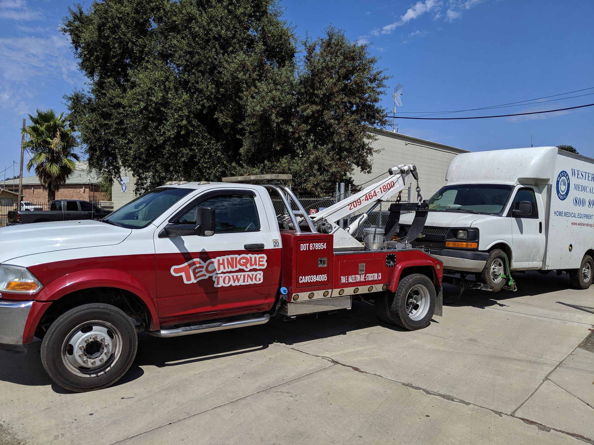Tow truck towing a white van. Truck is red and white with 