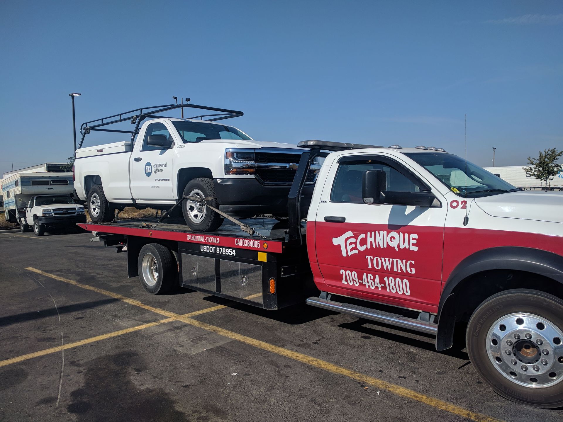 White pickup truck on a tow truck in a parking lot. Tow truck has 