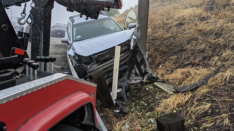 A tow truck is towing a car that has crashed into a pole.