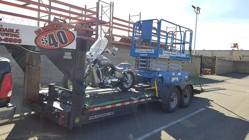 A trailer with a motorcycle on it is parked in a parking lot.