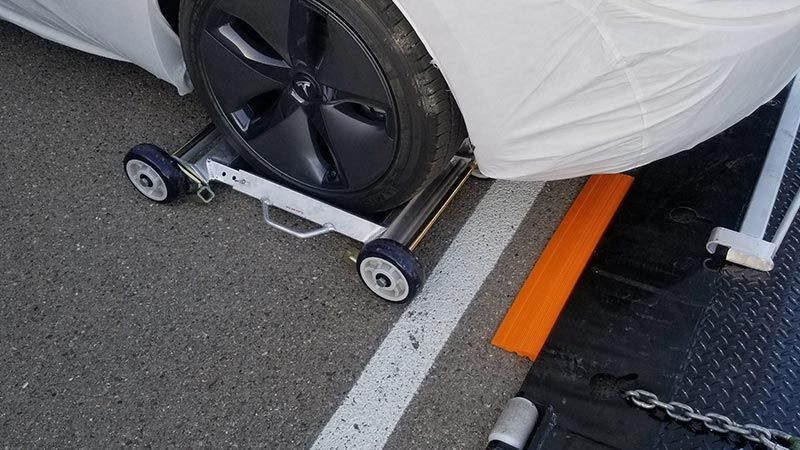 A car is sitting on a wheel dolly in a parking lot.