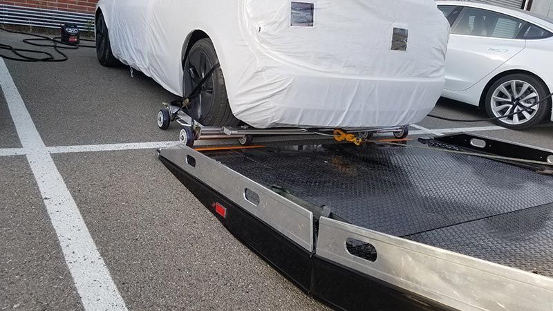 A white car is sitting on top of a tow truck.