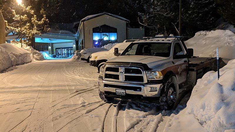 A tow truck is parked in the snow in front of a building