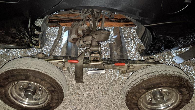 A wheelchair is sitting on a carpet next to a car.