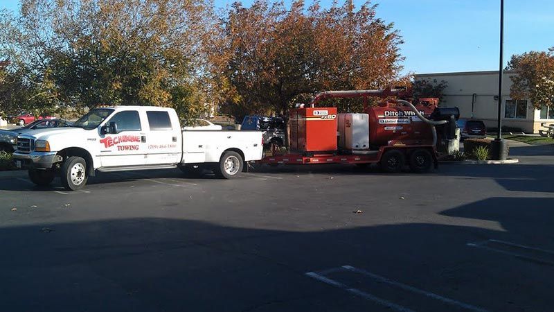 A white truck is pulling a red trailer in a parking lot