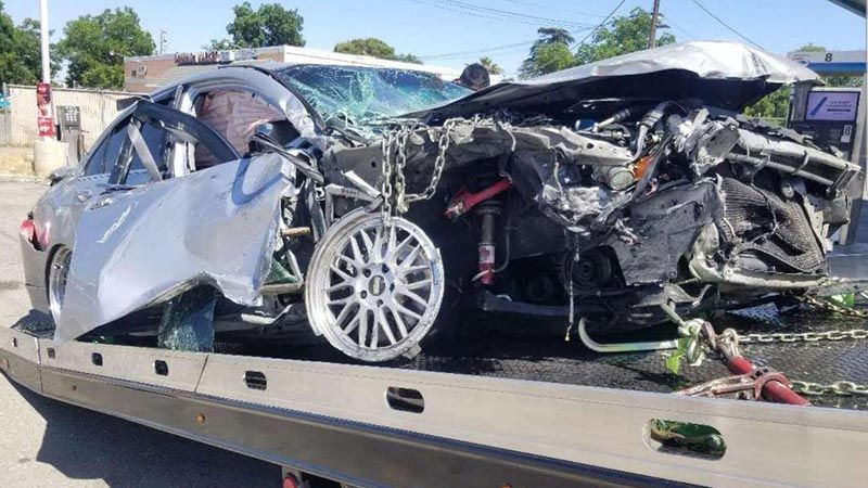 A wrecked car is sitting on top of a tow truck.