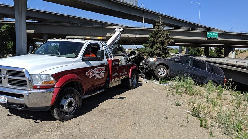 A tow truck is towing a car that has fallen off the road.