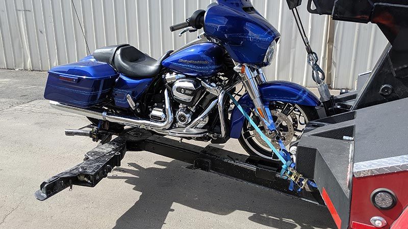 A blue harley davidson motorcycle is being towed by a tow truck.