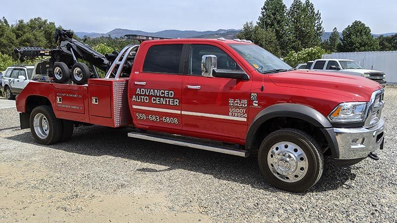 A red tow truck is parked in a gravel lot.