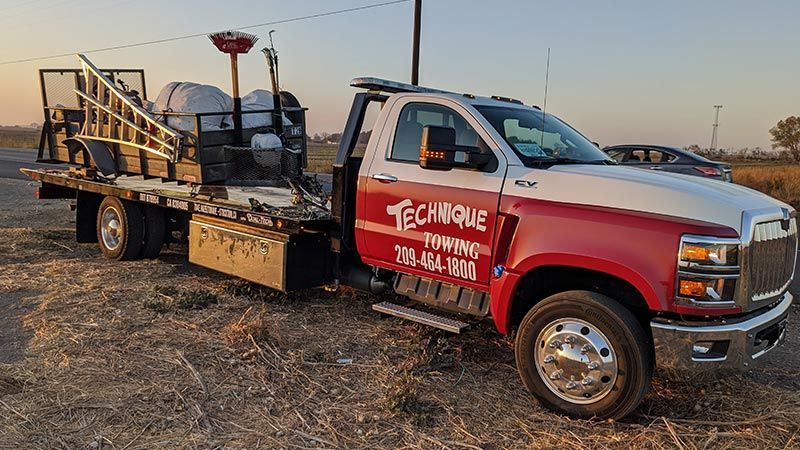 A red and white tow truck is parked in a field.