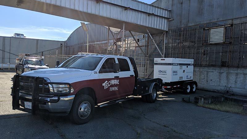 A red and white truck with a trailer attached to it is parked in front of a building.