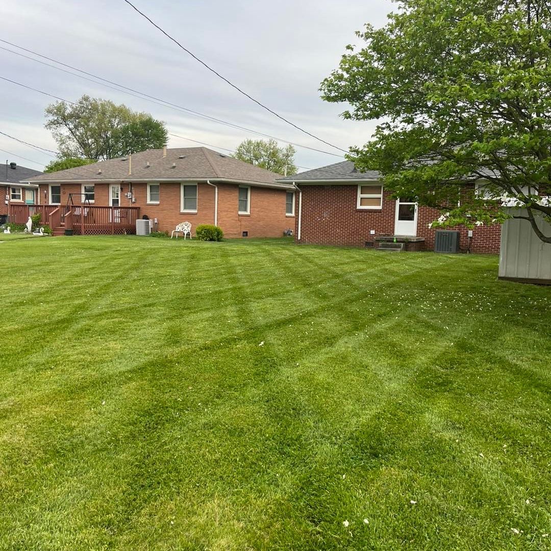 A lush green lawn in front of a brick house.