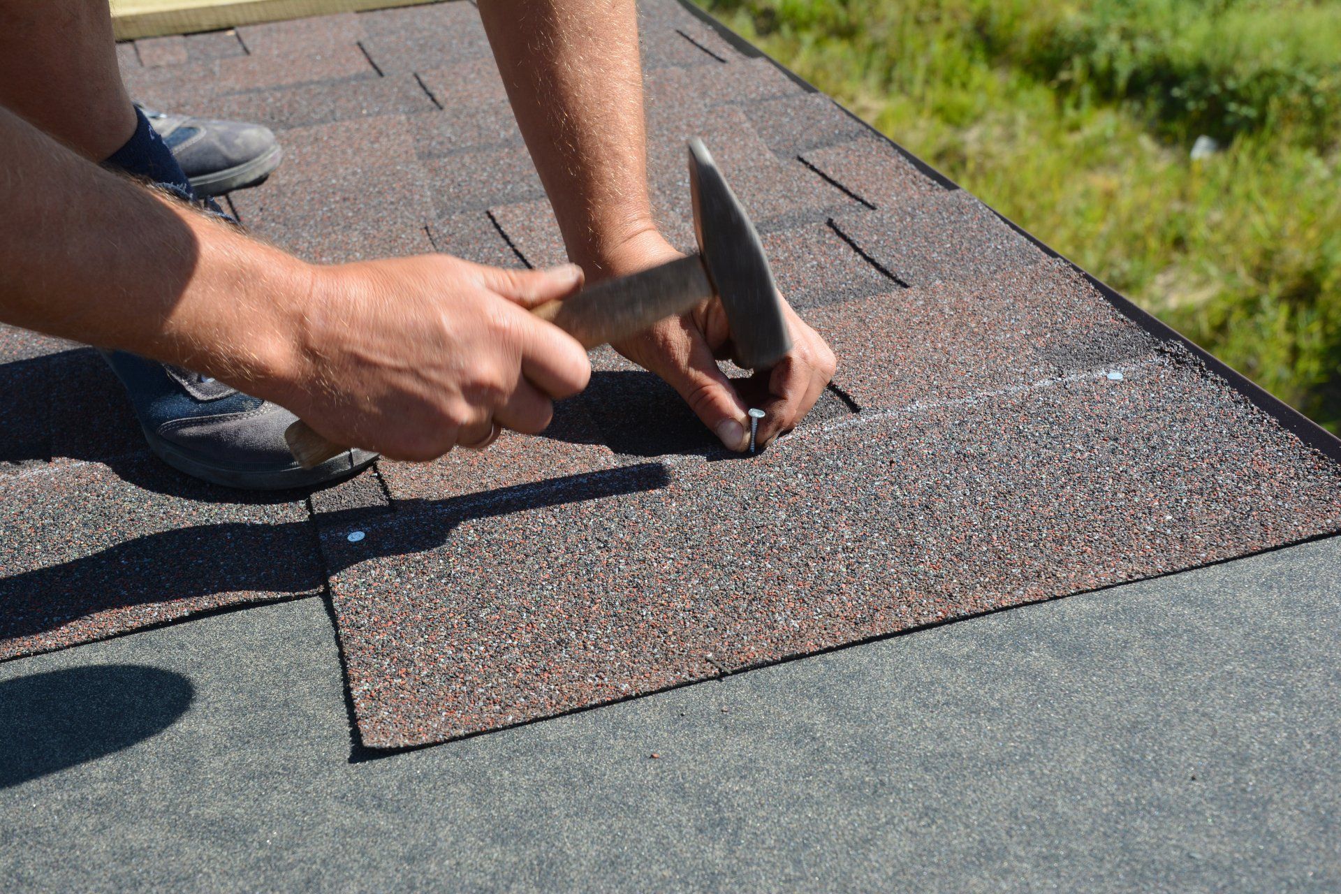 roofers nailing shingle on house