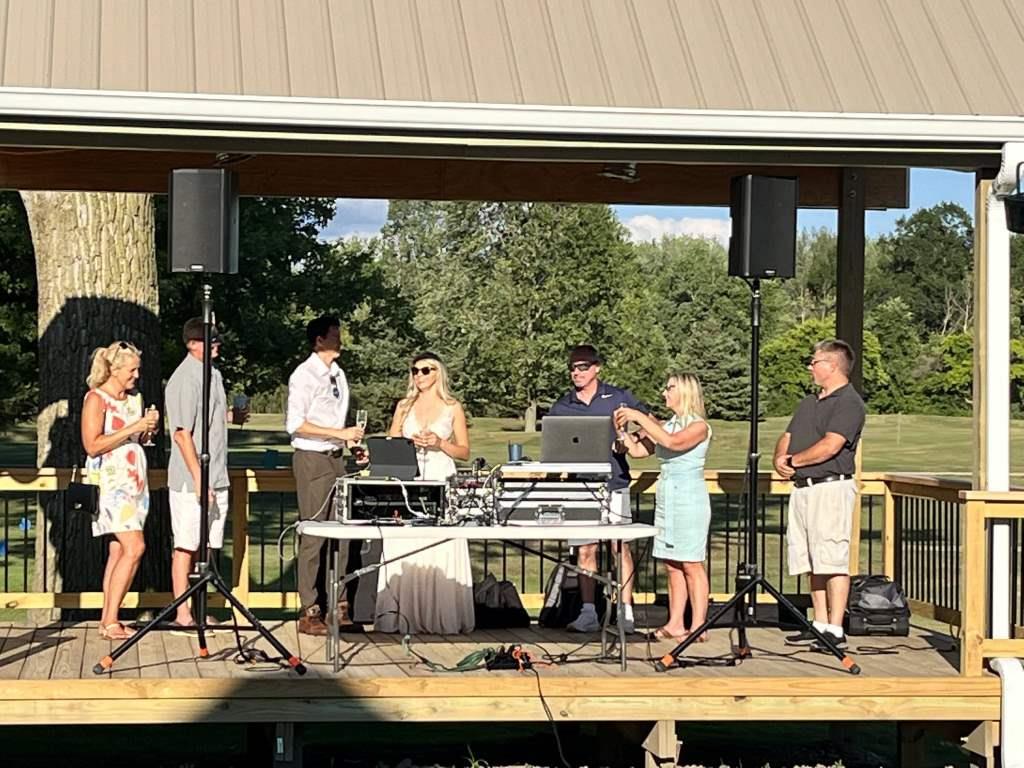 A group of people are standing around a table with a laptop on it.