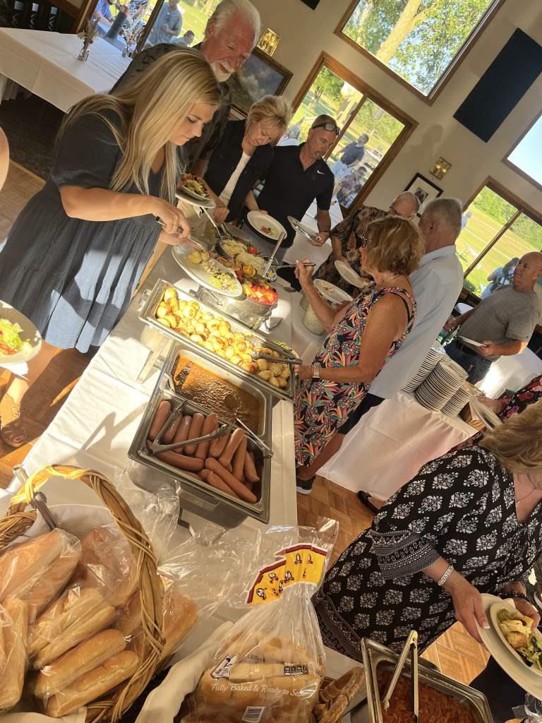 A group of people are standing around a table eating food