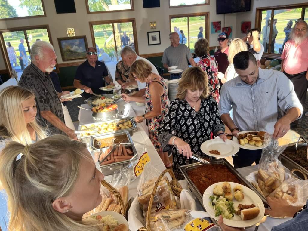 A group of people are standing around a table eating food.