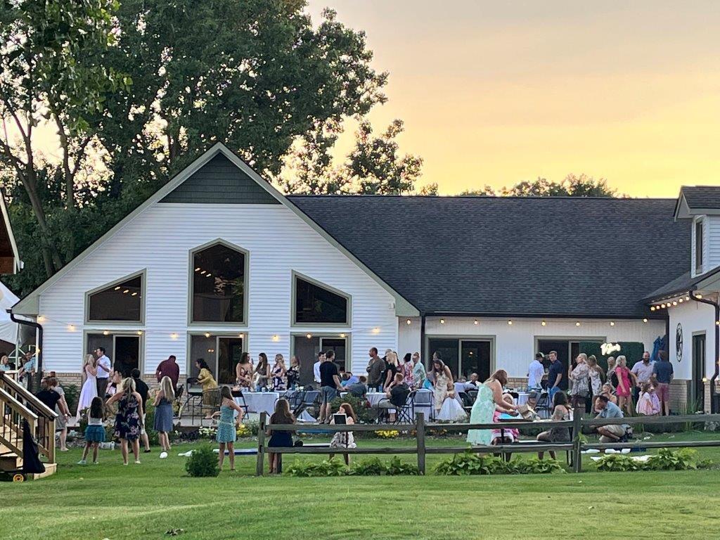 A large group of people are gathered in front of a large white building.